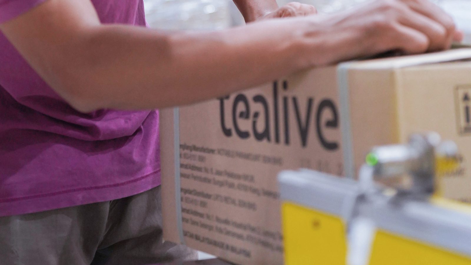 An operator sealing a Tealive carton of finished pearls.